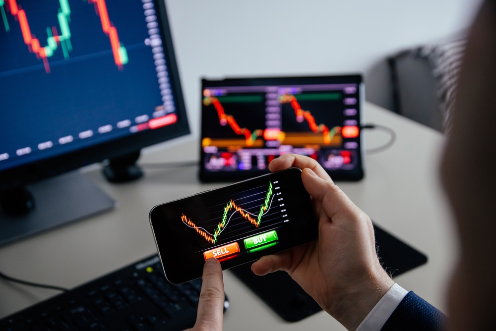 Business,Man,Using,A,Mobile,Device,To,Trade,Stocks,Or